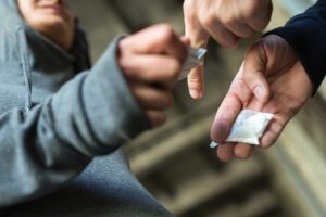 Close Up Of Addict Buying Dose From Drug Dealer